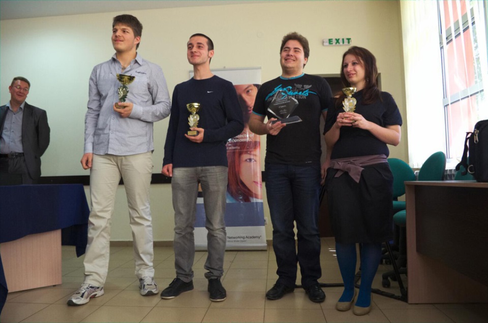 Класиралите се на първите места състезатели от Cisco Academy на ТУЕС държат купи, на заден план банер на Networking Academy